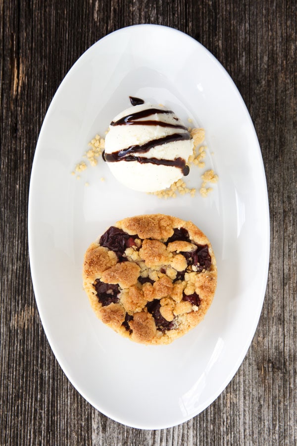 Joghurt-Vanilleeis mit Sauerkirschtörtchen, Schokosauce und Milch-Crumble